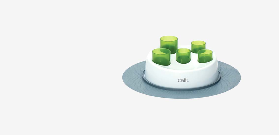 Catit Senses 2.0 Digger, a cat food puzzle toy with a white base and five green tubes on a grey mat