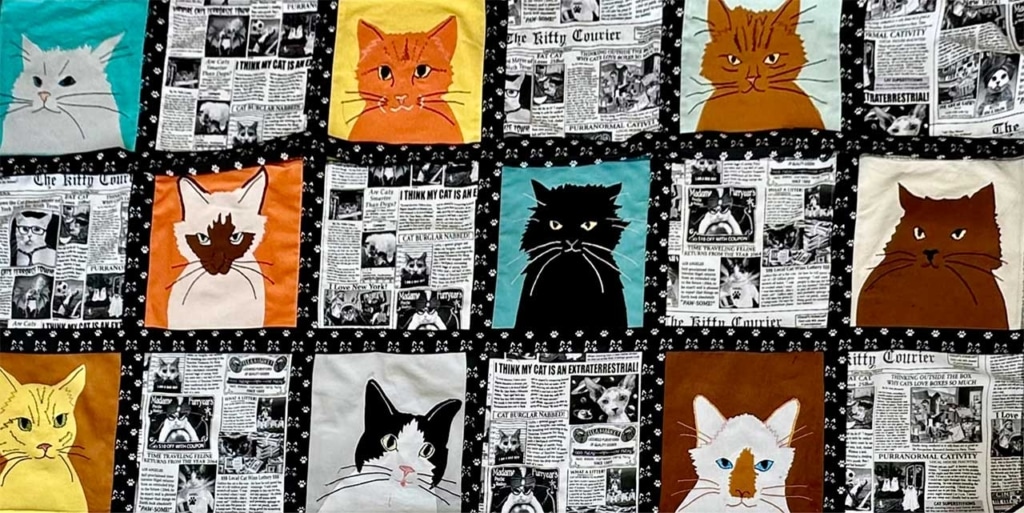 A quilt featuring a grid of cat portraits and newspaper-style fabric panels titled The Kitty Courier