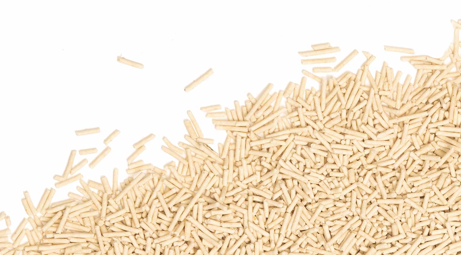 A pile of light-colored, cylindrical pea husk cat litter pellets against a white background