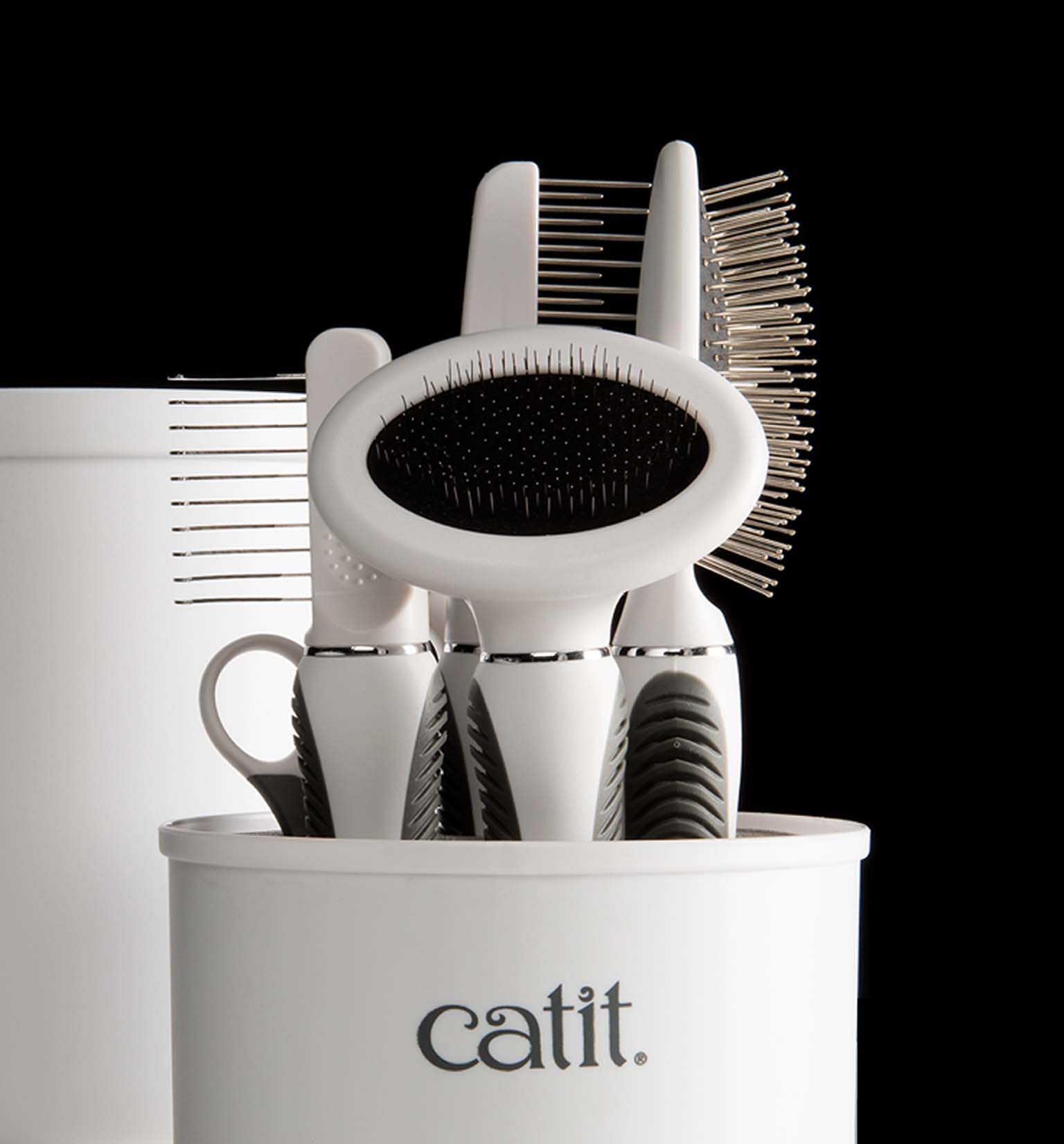 Catit grooming kit with various brushes and combs stored in a white container