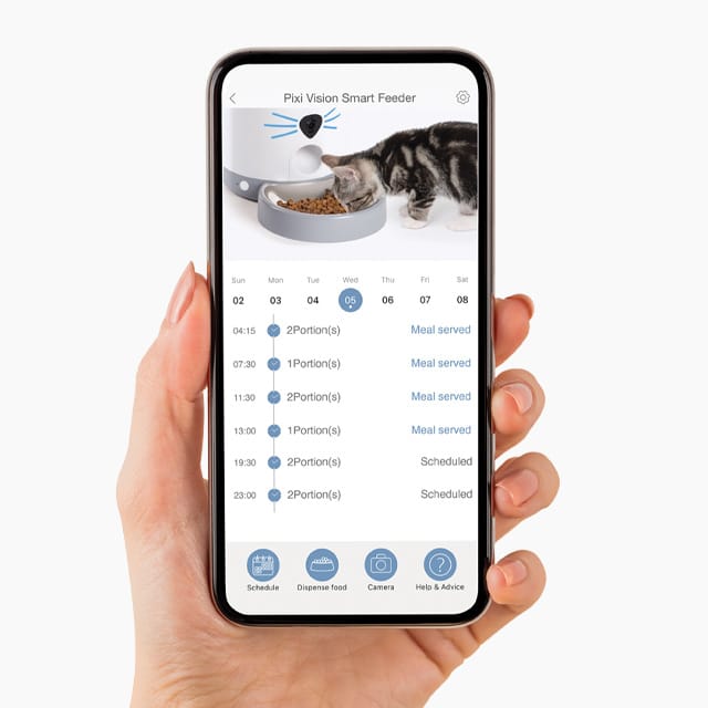 Hand holding a smartphone displaying the PIXI Smart Feeder app interface, showing a feeding schedule for a cat