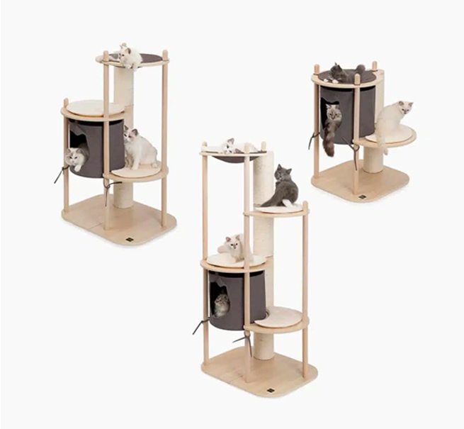 Three Catit Vesper Treehouse cat furniture units of varying heights, each featuring wooden platforms, scratching posts, and fabric-covered dens with cats resting on them.