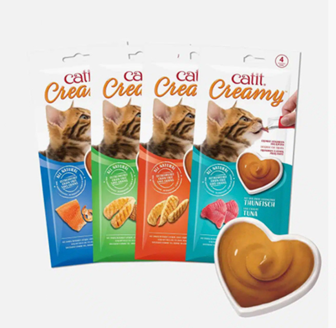 Four packages of Catit Creamy cat treats in various flavors, with a heart-shaped dish of the creamy treat in the foreground