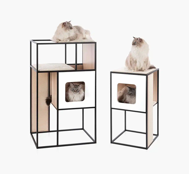 Two modern, black-framed cat towers with wooden cubbies and scratching panels, each occupied by a fluffy cat