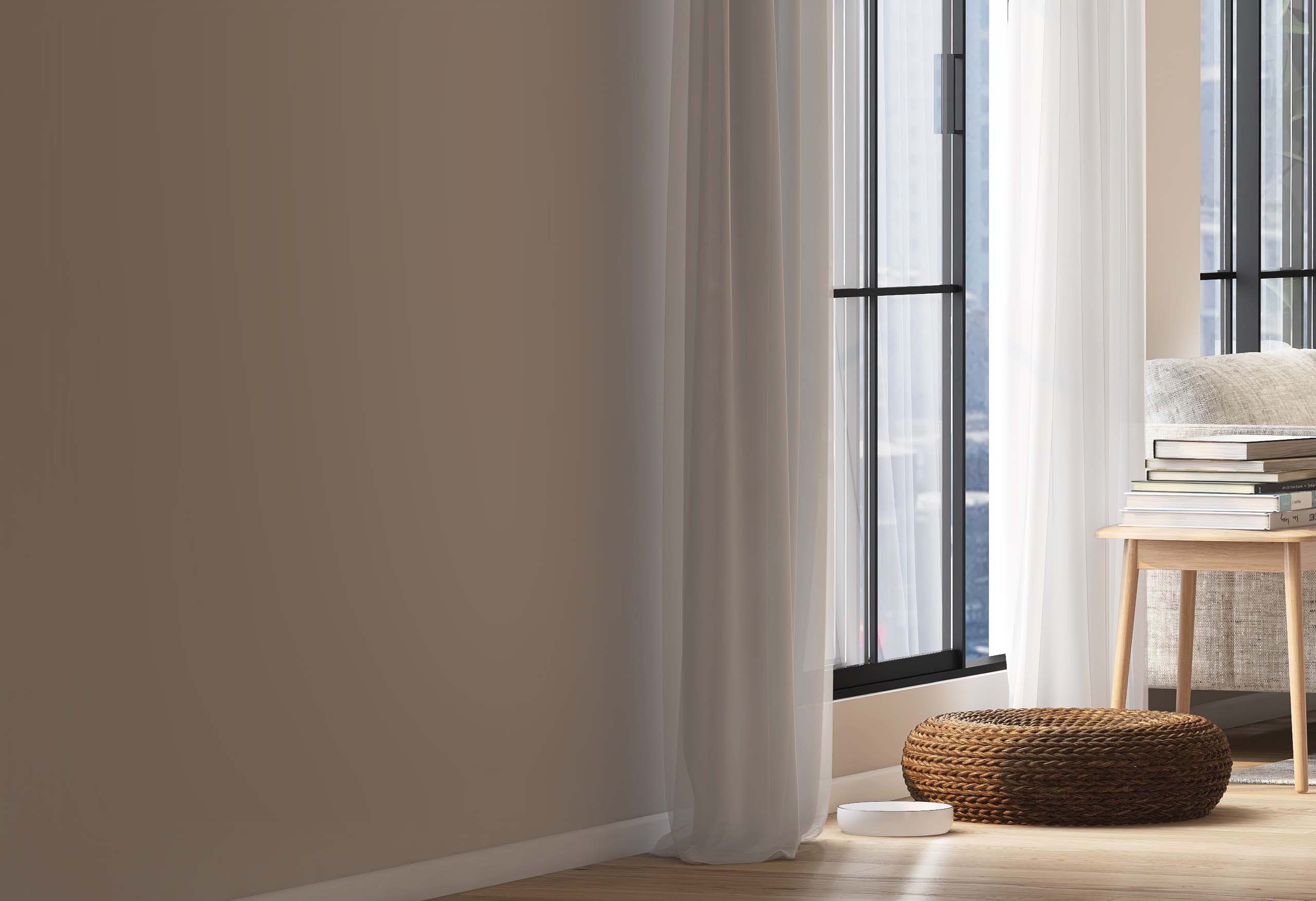 A white cat water fountain sits on a wooden floor next to a woven pet bed by a window with sheer curtains