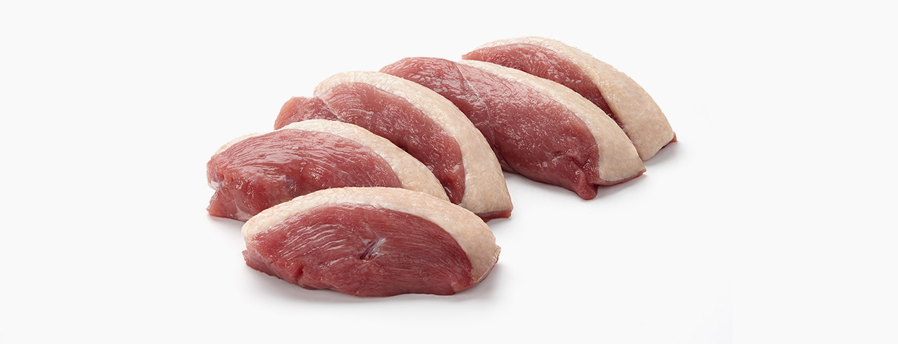 Four raw duck breast fillets with skin on, arranged on a white background