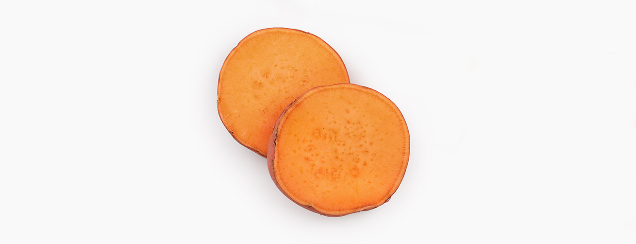 Two round slices of raw sweet potato on a white background