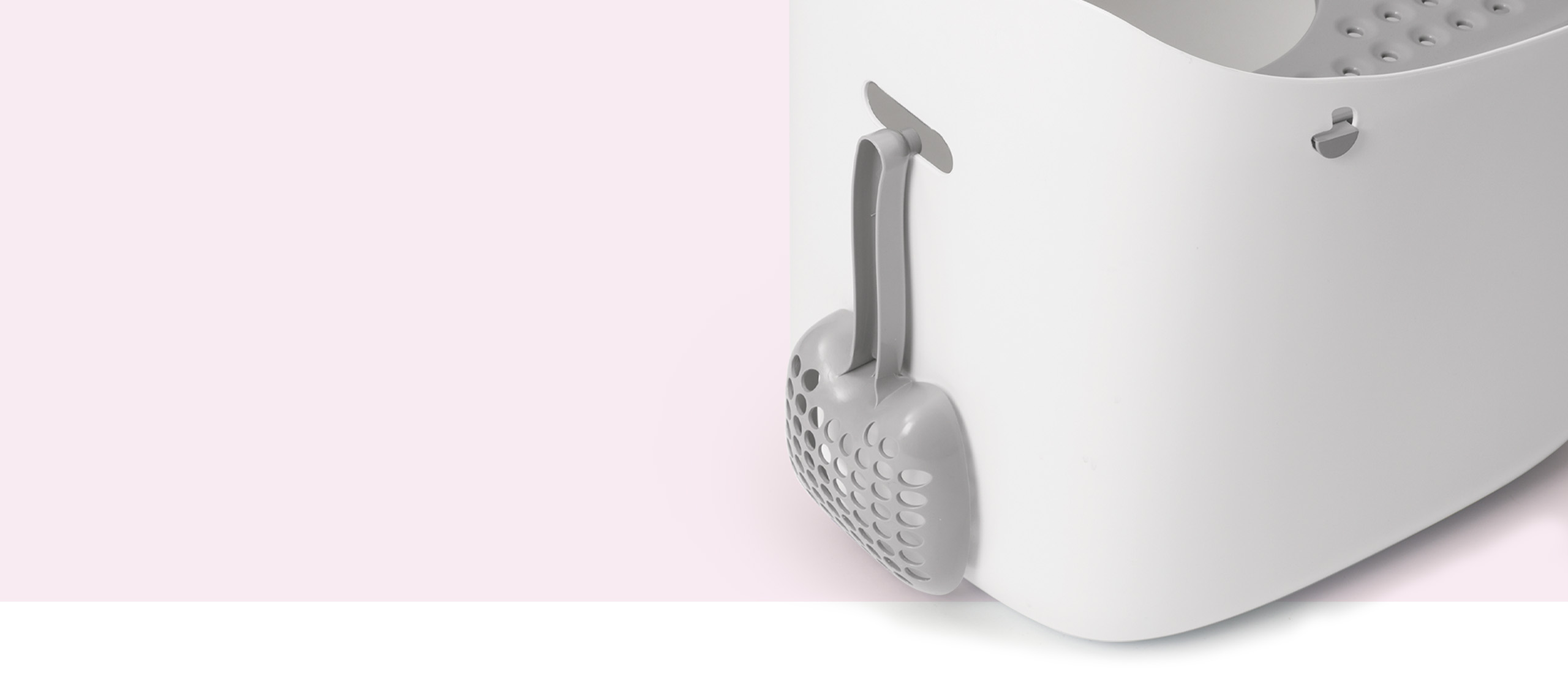 Grey cat litter scoop hanging on the side of a white Catit PIXI litter box