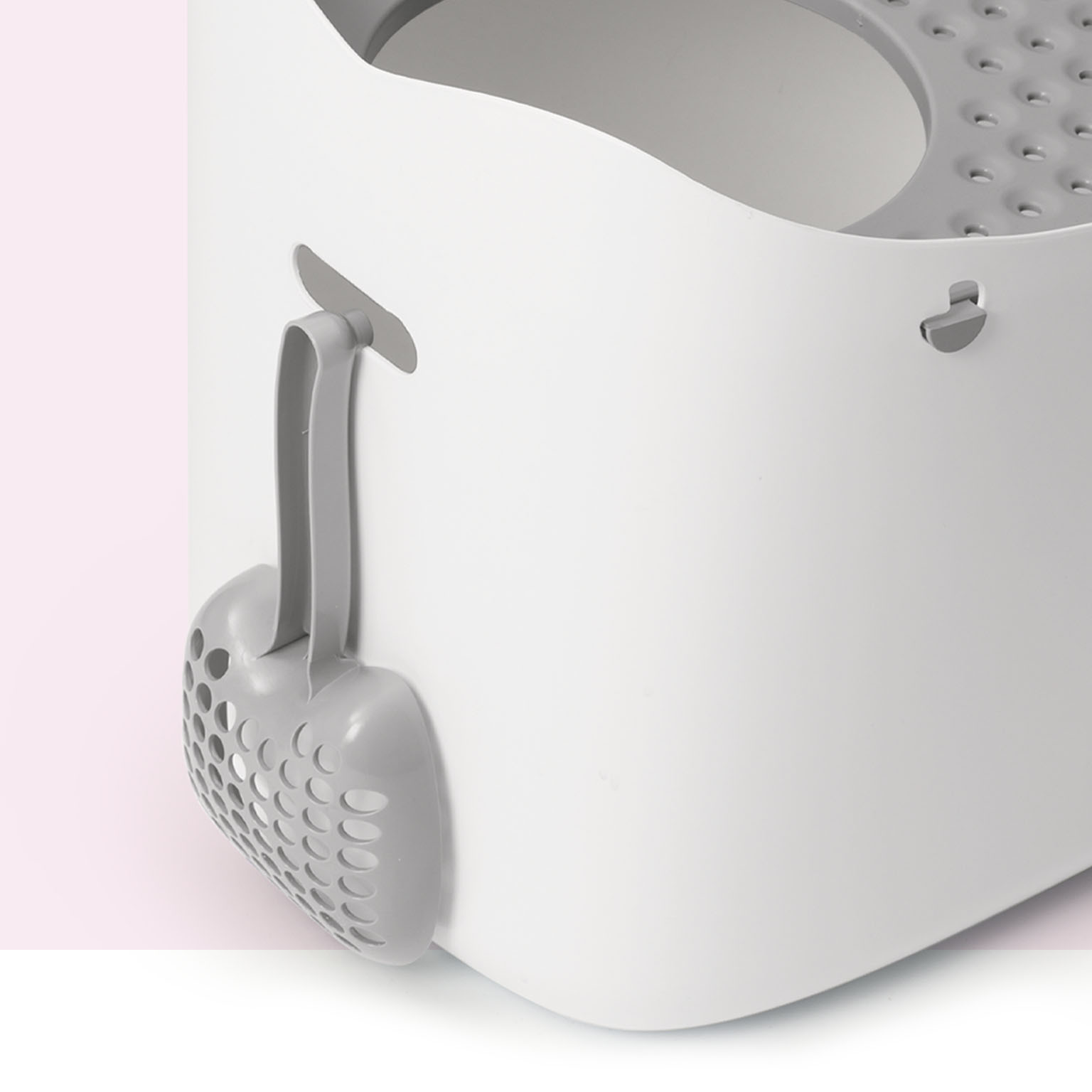 Grey cat litter scoop hanging on the side of a white Catit PIXI litter box