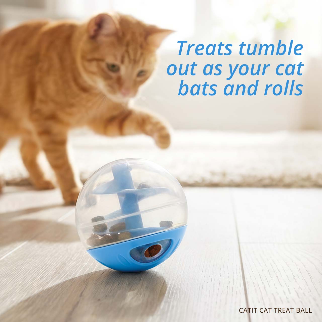An orange tabby cat bats at a Catit treat ball, which releases food as it rolls across the floor