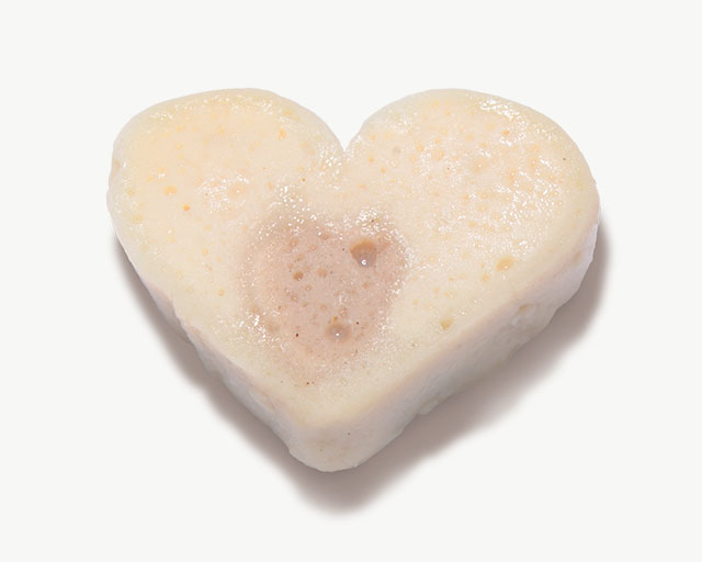 A heart-shaped cat treat with a light-colored exterior and a darker, textured center