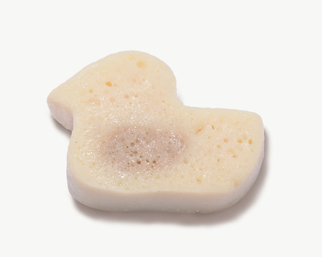 A duck-shaped cat treat with a porous, light-colored texture and a darker center