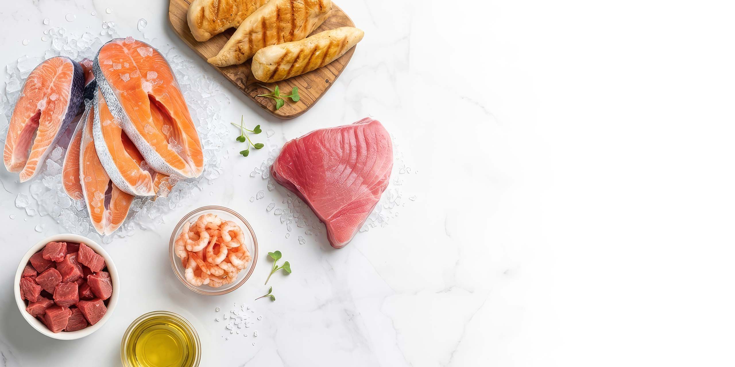 Raw salmon, tuna, shrimp, cubed beef, and grilled chicken on a marble surface