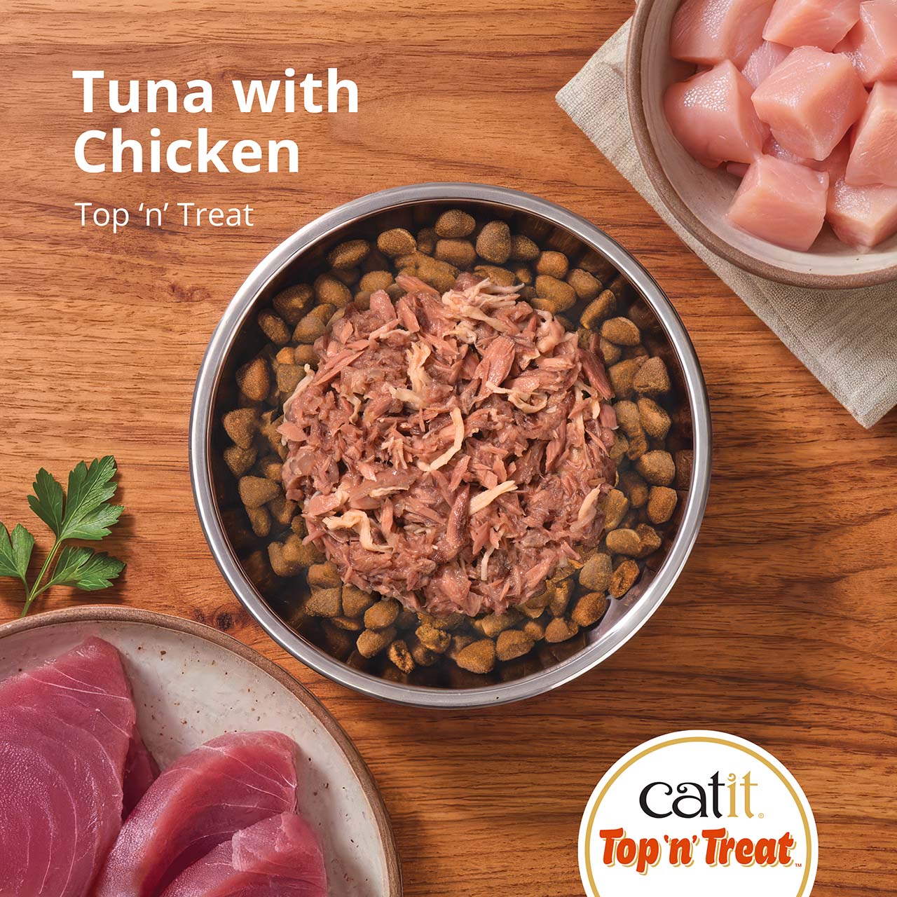Catit Top 'n' Treat Tuna with Chicken cat food topper served over dry kibble in a bowl with raw tuna and chicken nearby