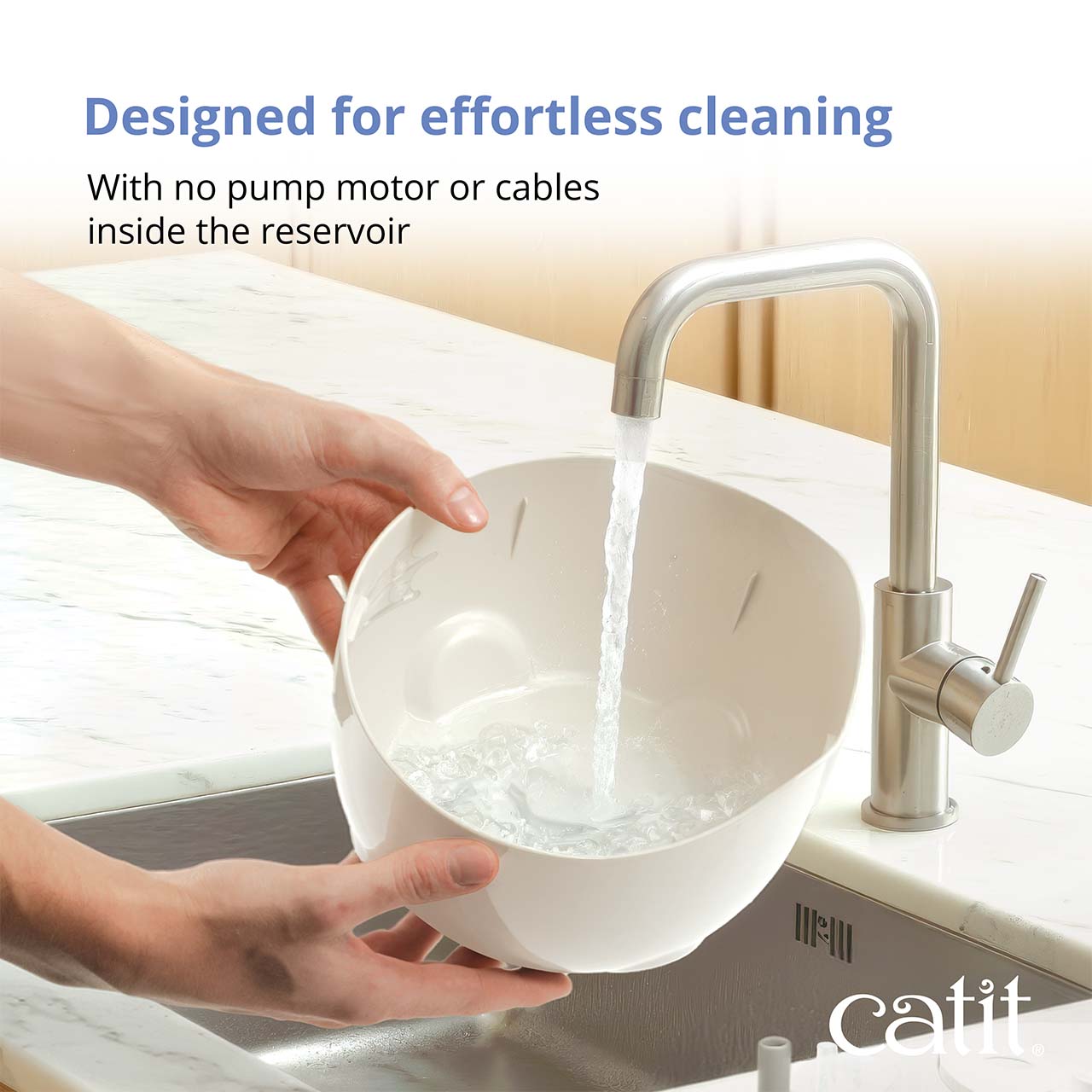 A person rinsing the reservoir of a Catit PIXI water fountain under a kitchen faucet to highlight its easy-to-clean design