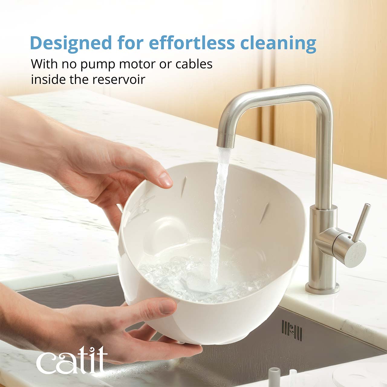 A person rinsing a Catit PIXI fountain reservoir under a kitchen faucet, highlighting its easy-to-clean, cordless design