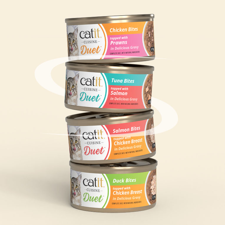 A vertical stack of four Catit Cuisine Duet cat food cans in various flavors including Chicken, Tuna, Salmon, and Duck