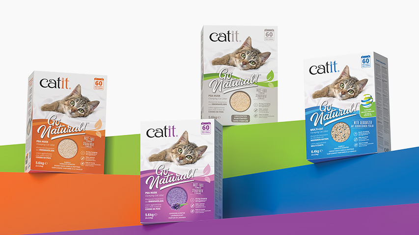 Four packages of Catit Go Natural clumping cat litter in various scents and formulas arranged on colorful platforms