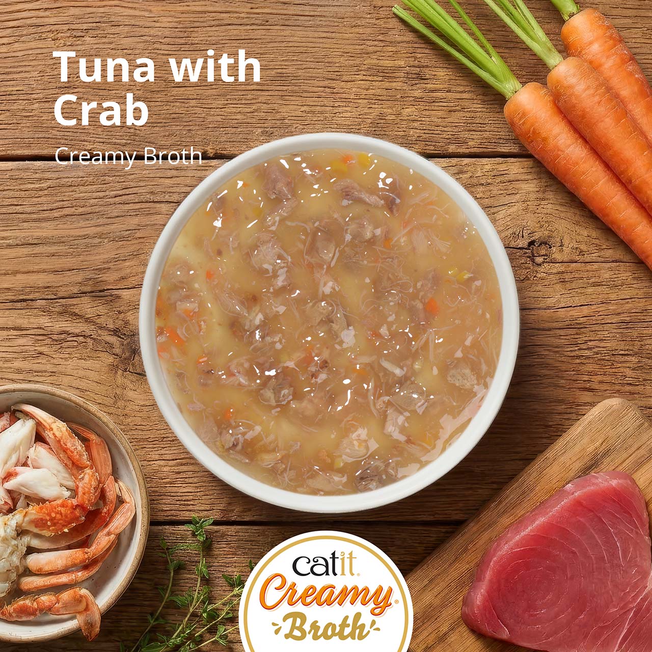 A bowl of Catit Creamy Broth with tuna and crab, surrounded by fresh ingredients including carrots, crab, and raw tuna