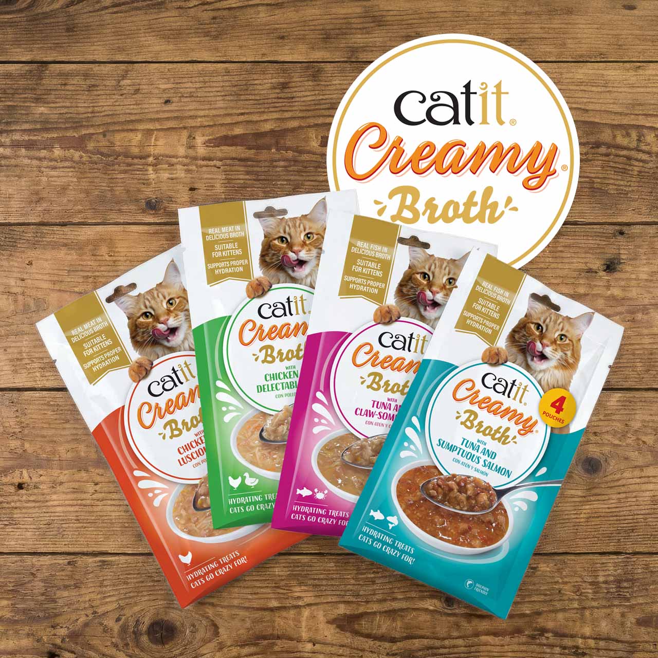 Four pouches of Catit Creamy Broth cat treats in chicken and tuna flavors arranged on a wooden surface