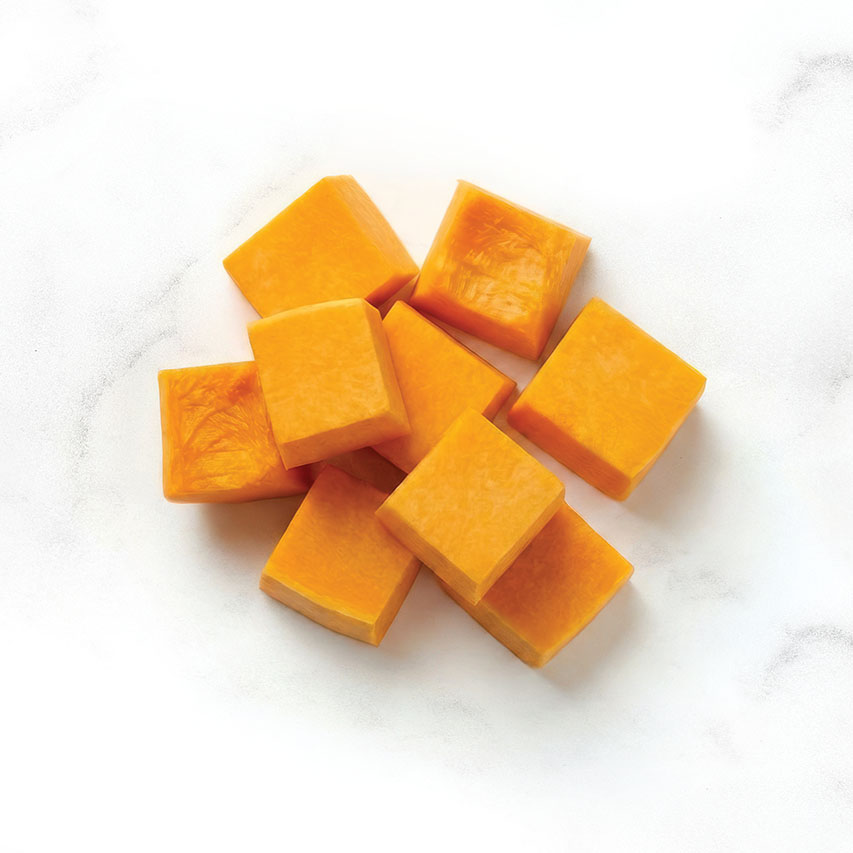 Cubed pieces of raw pumpkin on a white marble surface