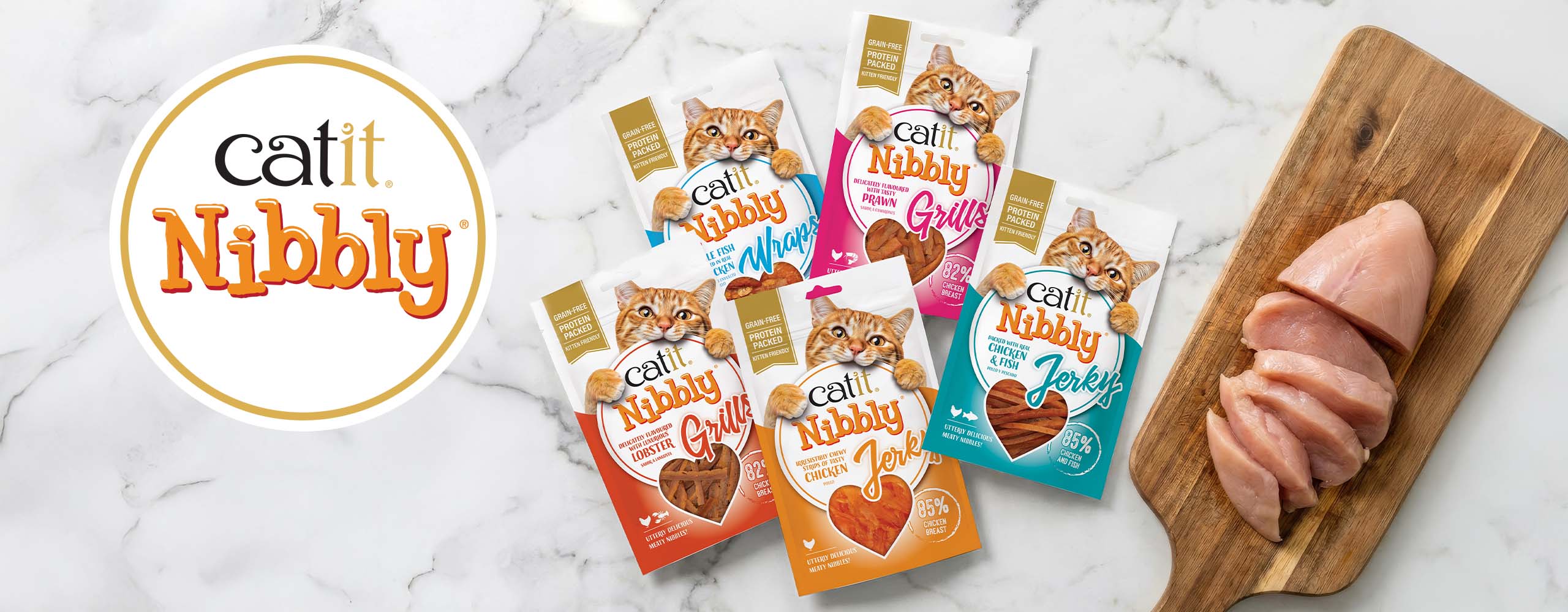 Catit Nibbly cat treat packaging featuring various flavors like chicken, fish, prawn, and lobster next to raw chicken breast