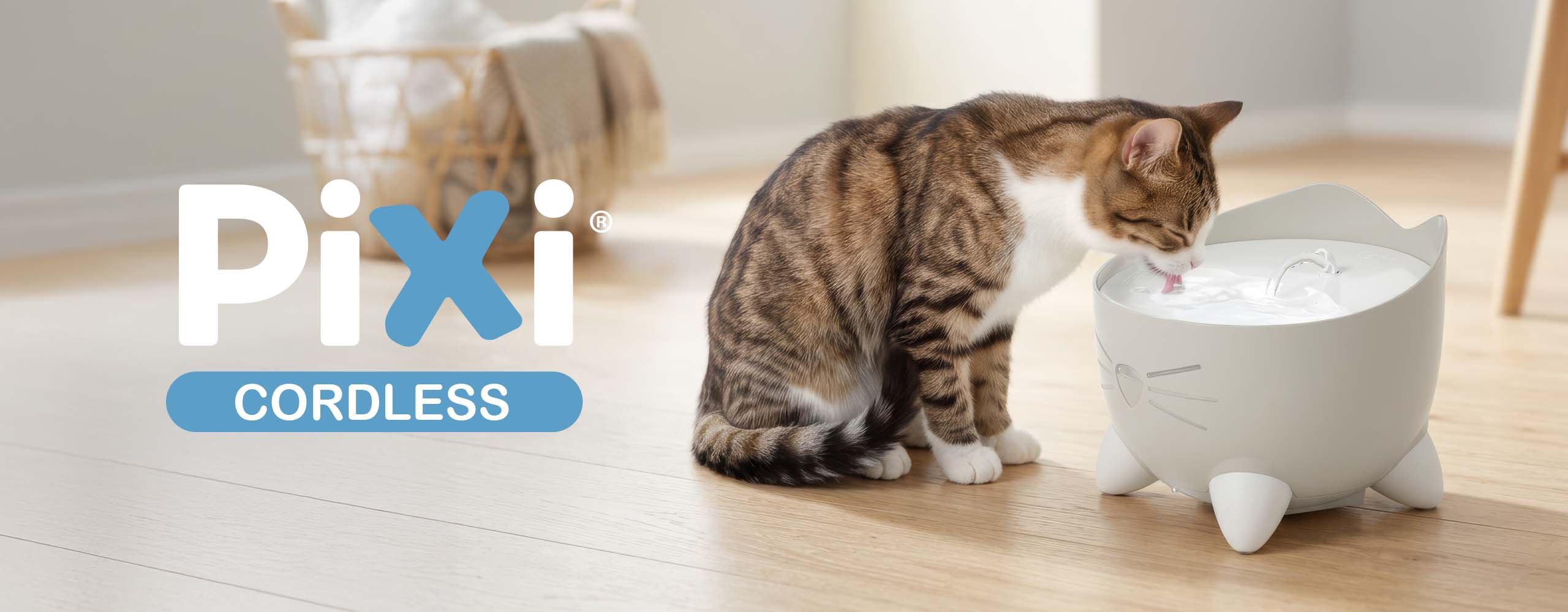A tabby cat drinking from a white PIXI cordless cat water fountain shaped like a cat face