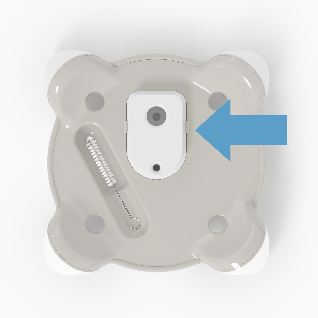 Top view of a Catit PIXI fountain base with a cleaning brush and a blue arrow pointing to the pump housing