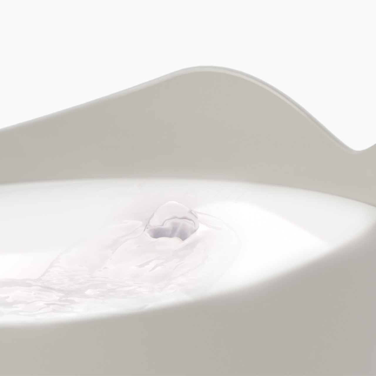 Close-up of water bubbling from the top of a white Catit PIXI fountain