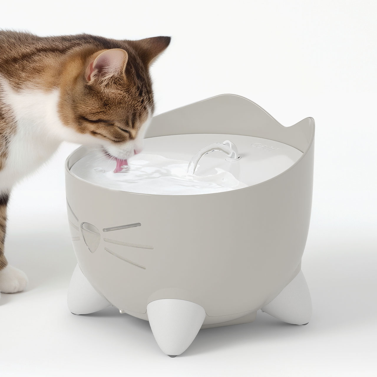 A tabby cat drinking water from a light gray Catit PIXI cat fountain shaped like a cat head