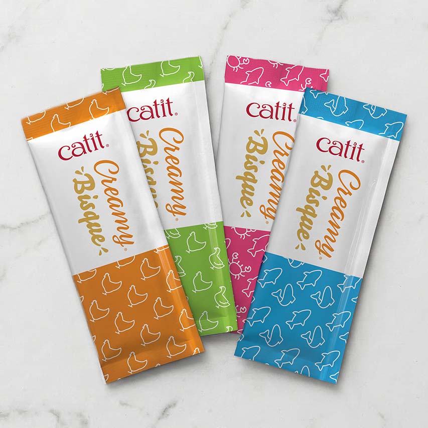 Four Catit Creamy Bisque cat treat pouches in orange, green, pink, and blue packaging