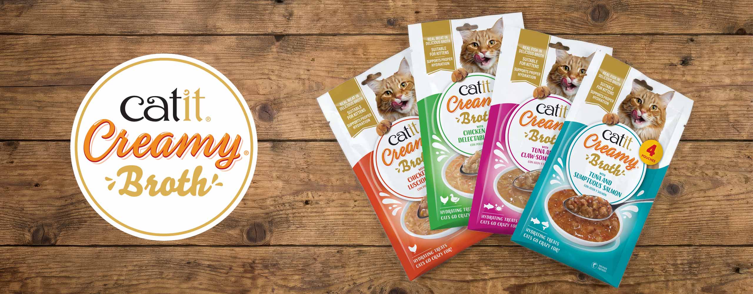 Catit Creamy Broth cat treat pouches in four flavors displayed on a wooden surface