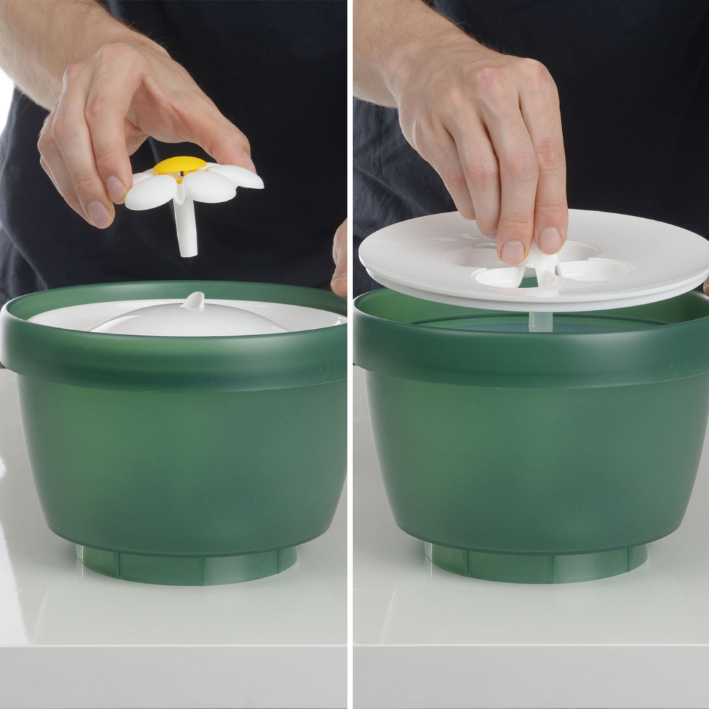 Hands assembling a green Catit PIXI flower fountain by attaching the flower spout to the lid