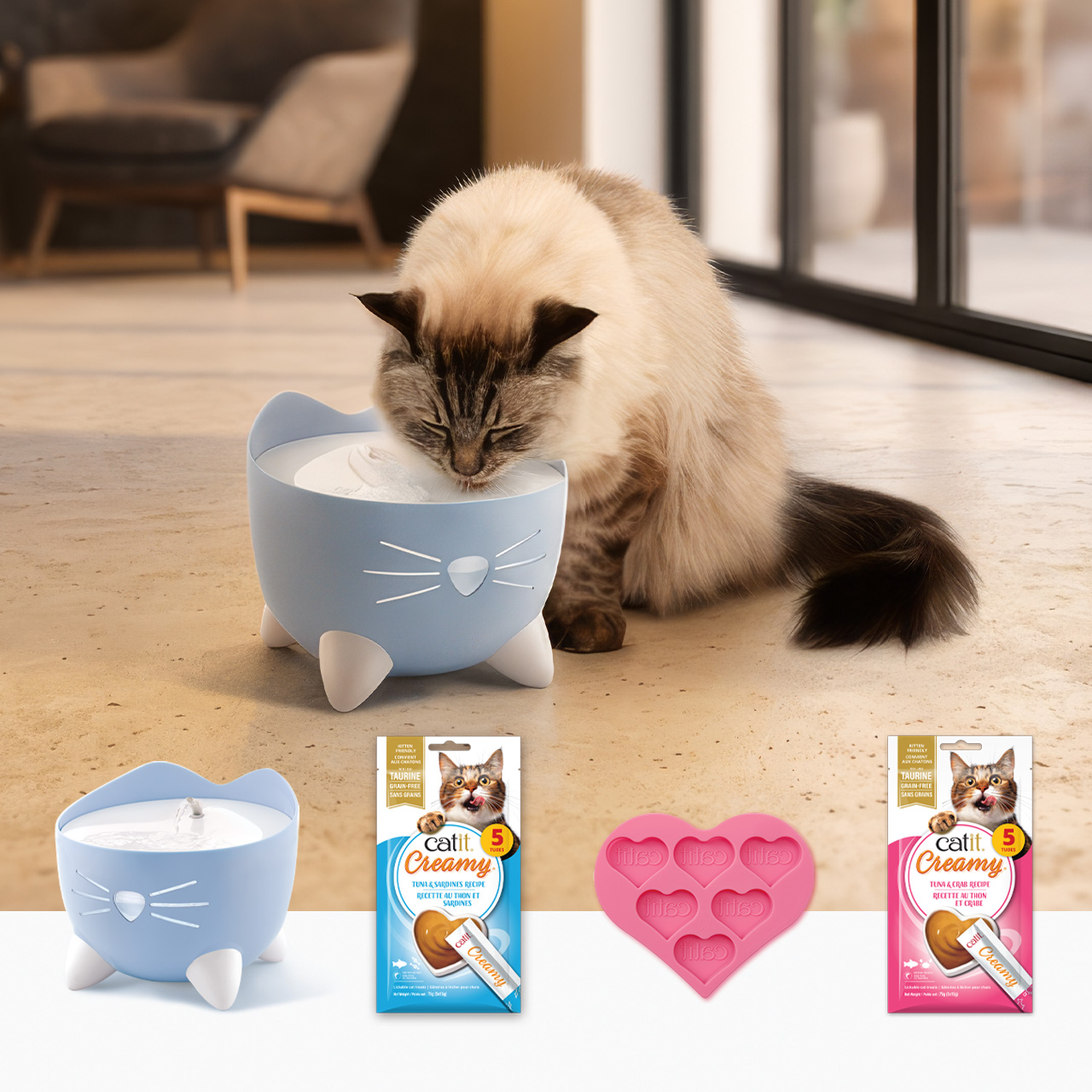 A cat drinking from a blue cat-shaped water fountain, with Catit Creamy treats and a heart-shaped mold displayed below