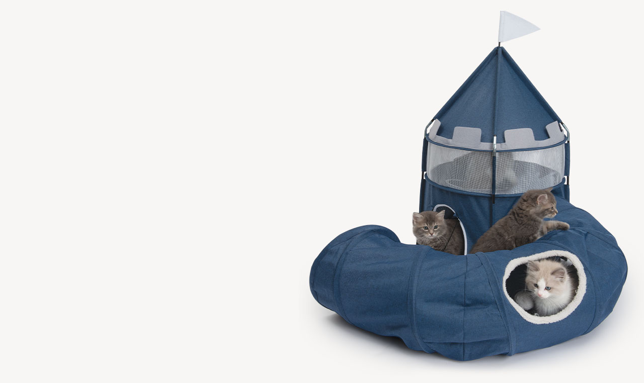 Three kittens playing in and around a blue, castle-shaped cat tent and tunnel system