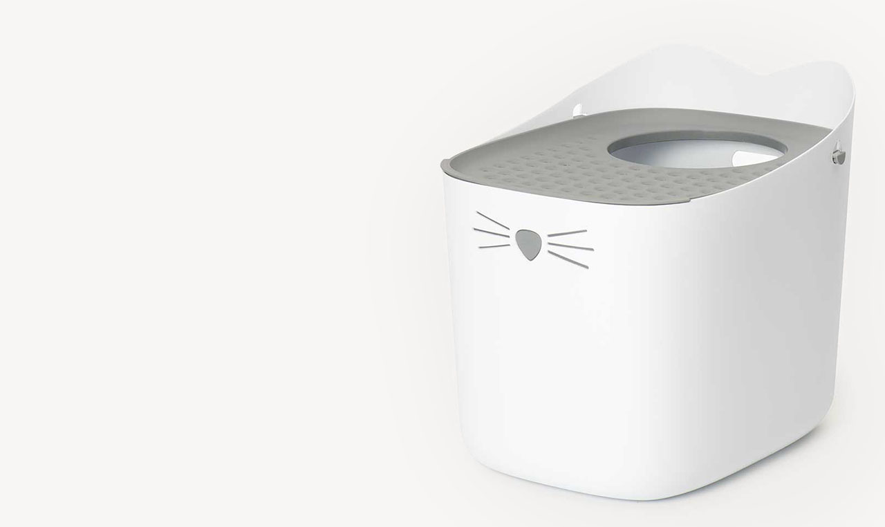 White PIXI cat litter box with a grey top entry lid and a cat face design on the front