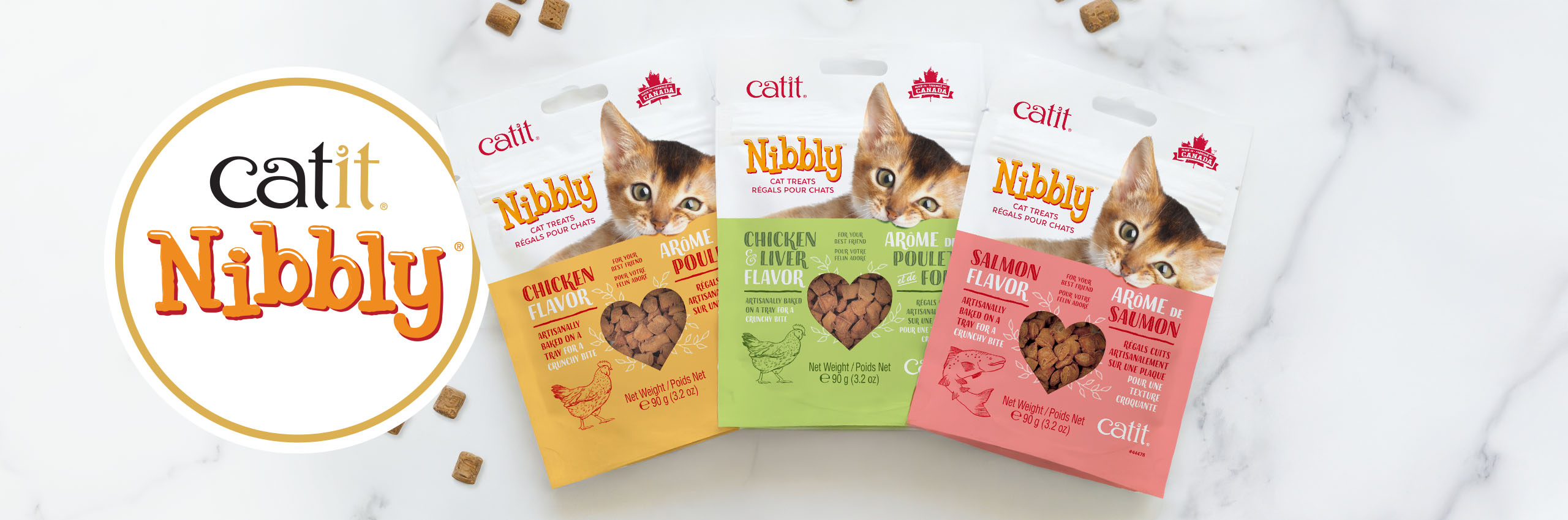 Three packages of Catit Nibbly cat treats in Chicken, Chicken & Liver, and Salmon flavors on a white marble surface