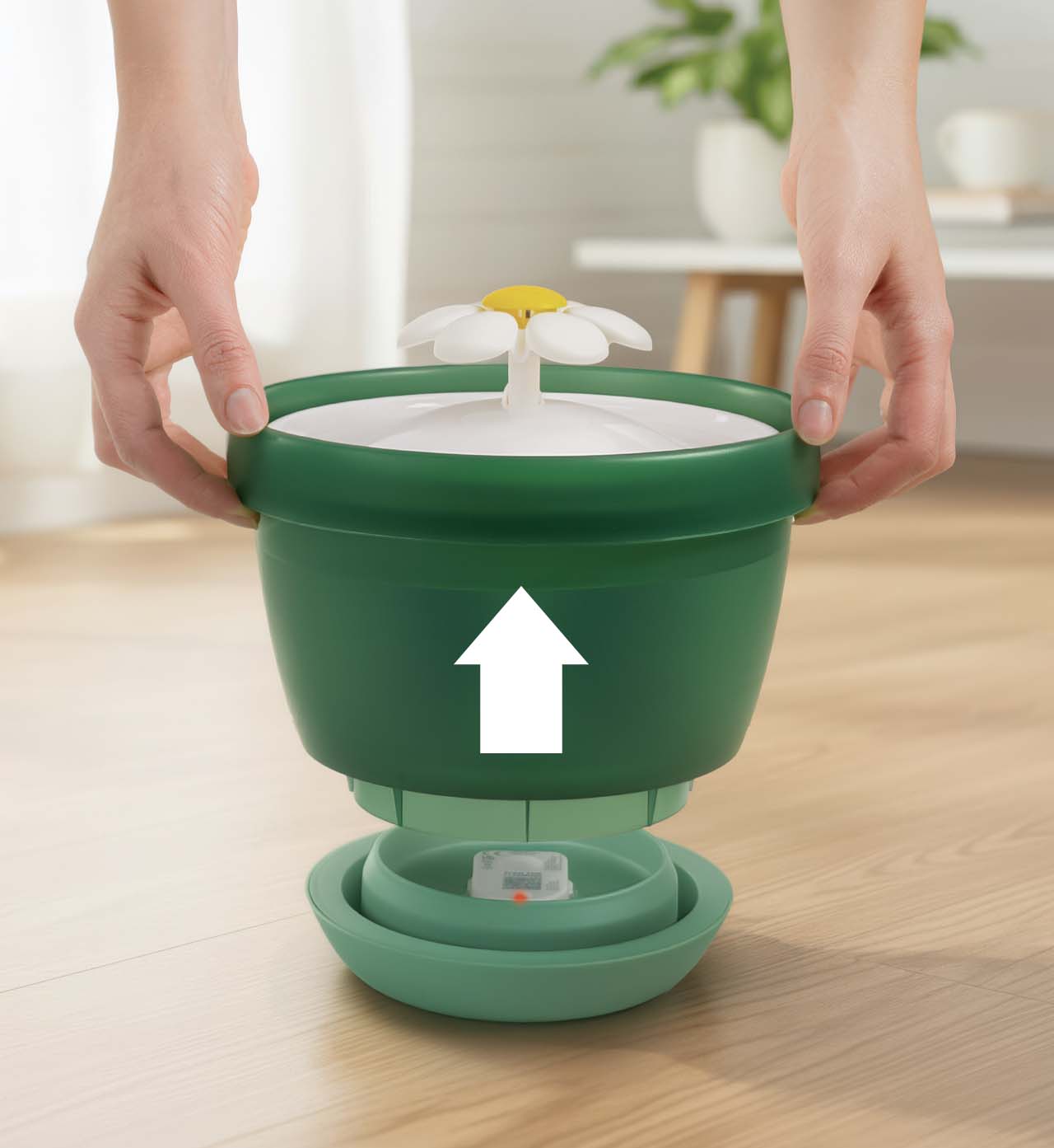 Hands lifting the green top section of a Catit flower water fountain off its base