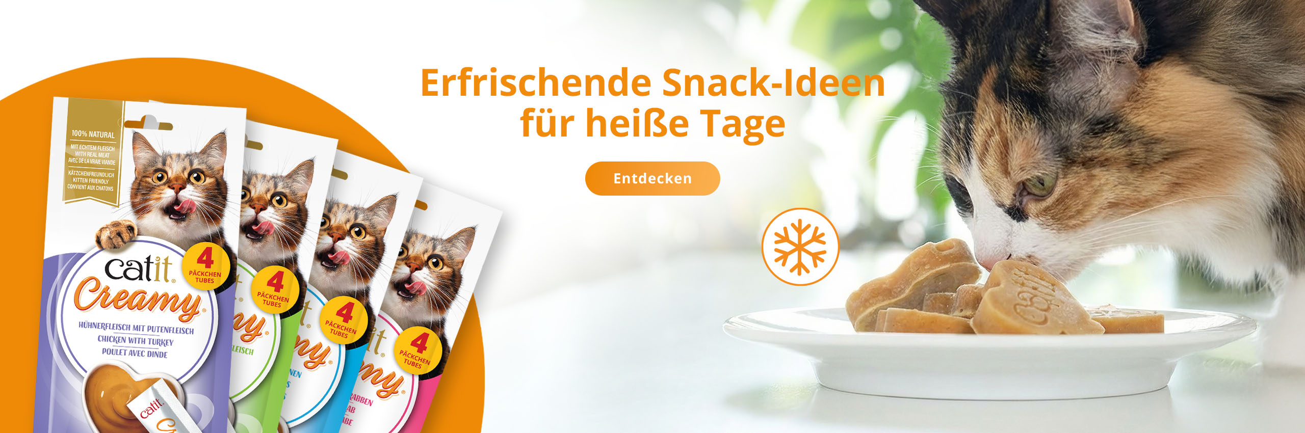 Katze frisst gefrorene Catit Creamy Herz-Leckerlis von einem Teller; in der linken Ecke sind vier Catit Creamy-Verpackungen zu sehen.