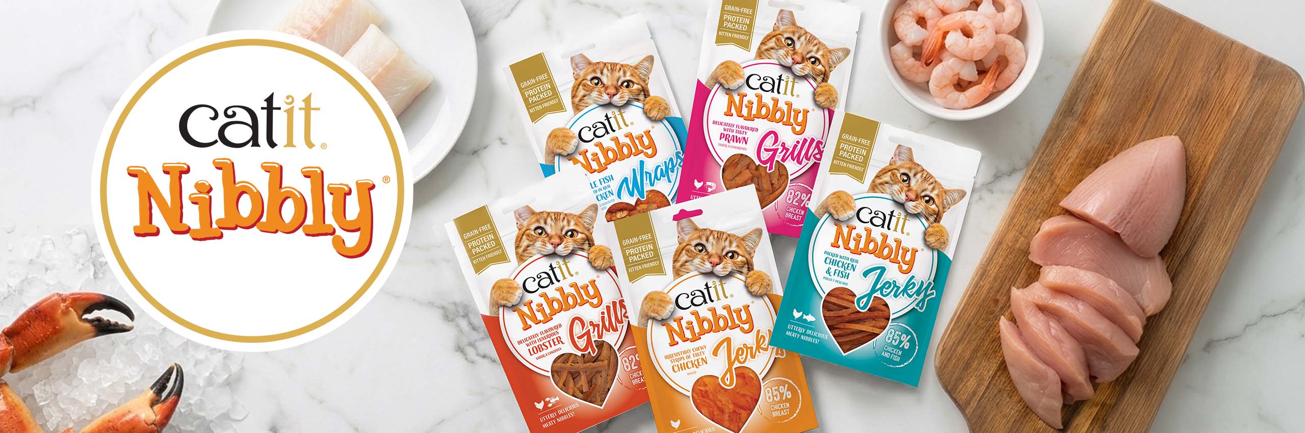 Catit Nibbly cat treats in various flavors, including chicken, fish, lobster, and prawn, displayed with fresh ingredients
