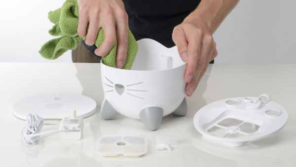 Person cleaning inside of PIXI Mini Fountain with cloth