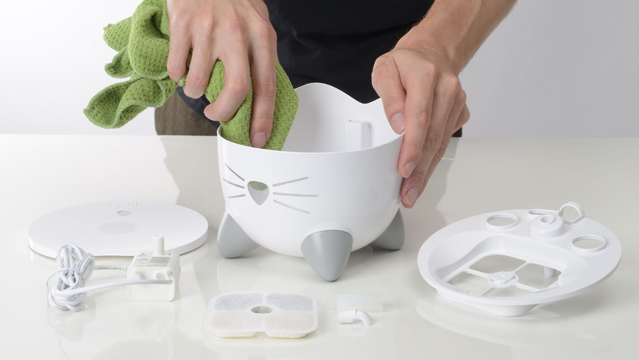 Person cleaning inside of PIXI Mini Fountain with cloth