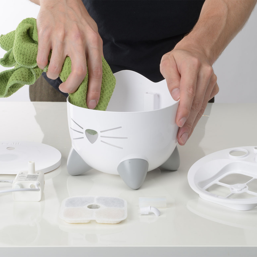 Person cleaning inside of PIXI Mini Fountain with cloth