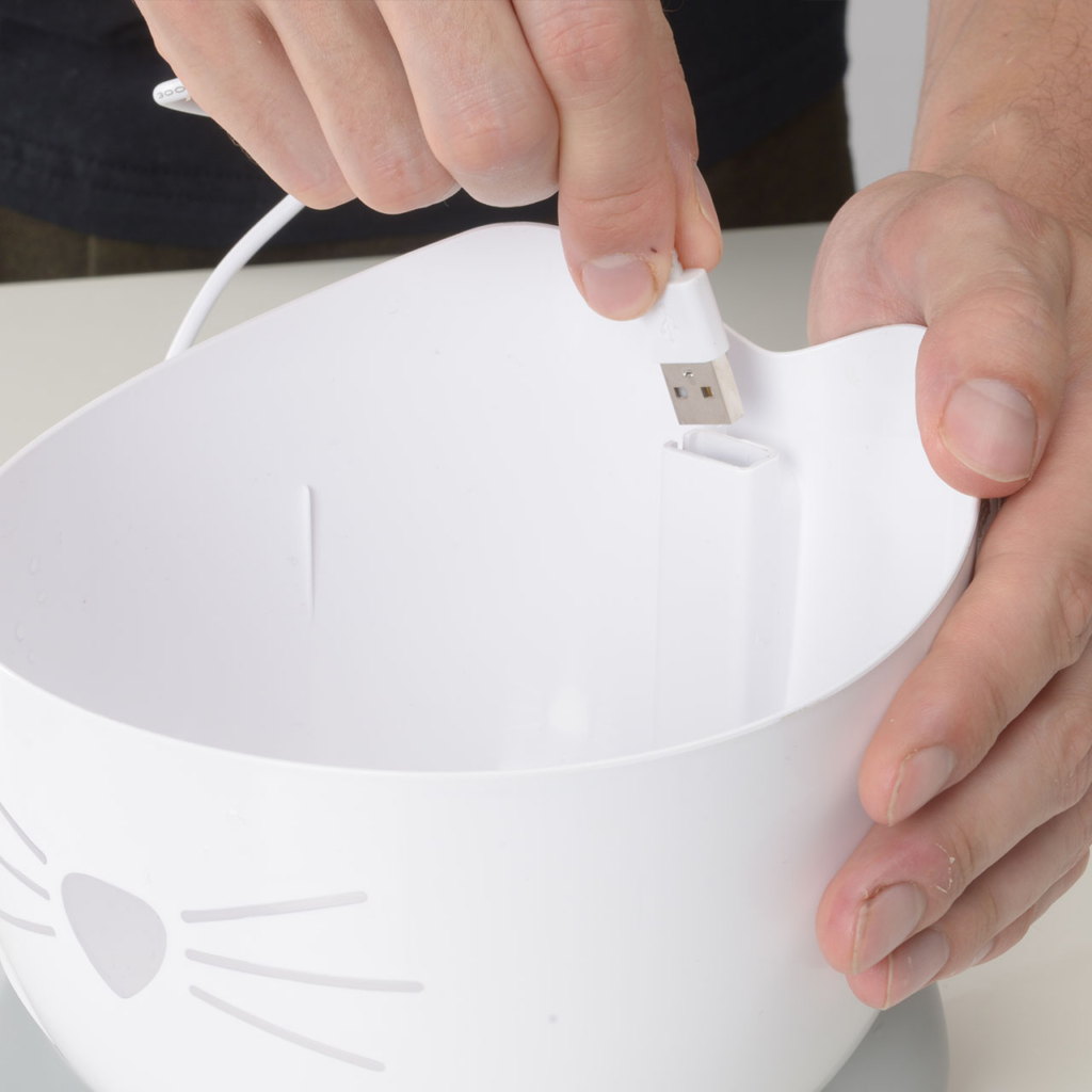 Person inserting pump cable in the back of the PIXI Mini fountain