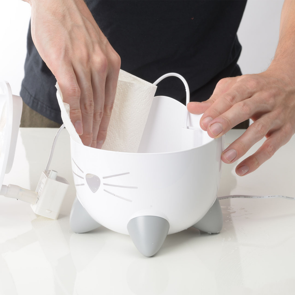 Person cleaning the inside of the PIXI Mini Fountain with a paper towel
