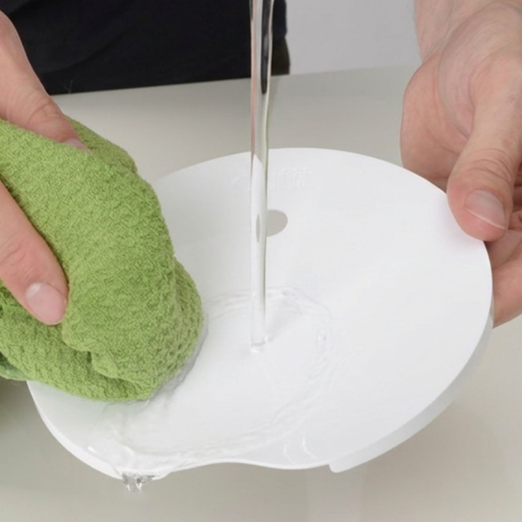 Hands cleaning PIXI mini fountain top with cloth