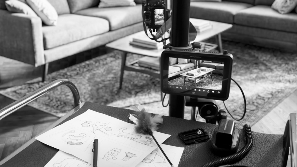an illustrated storyboard lying on a table next to a camera in a living room.