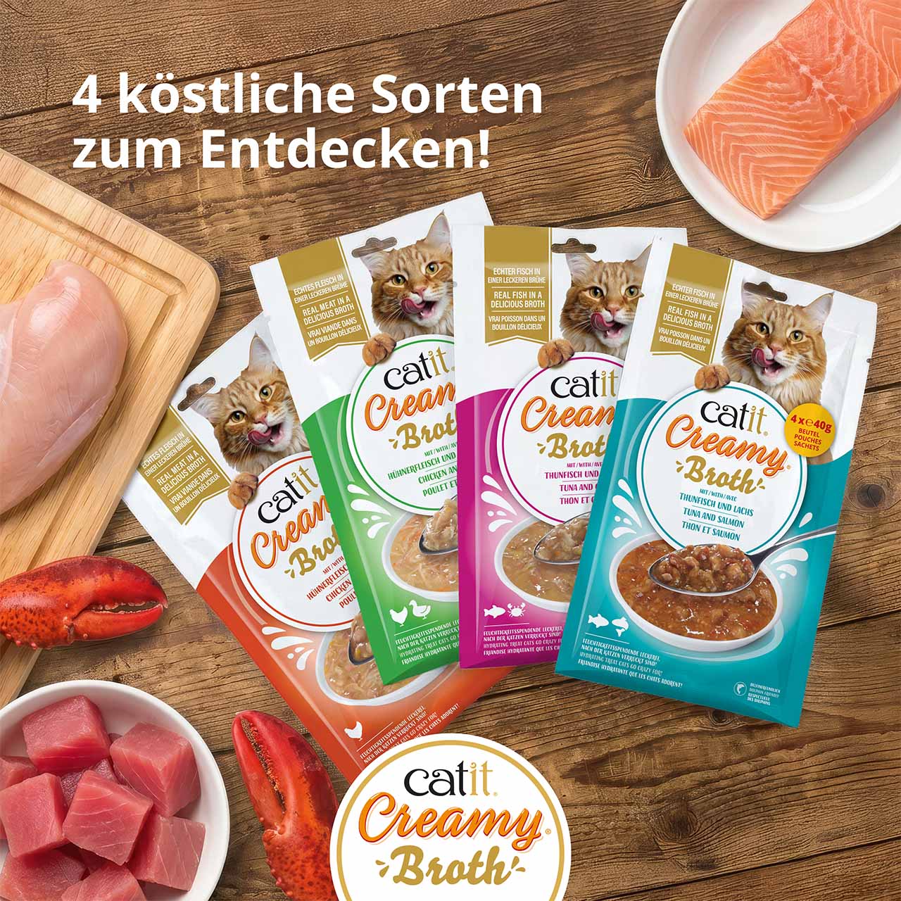Draufsicht auf alle Catit Creamy Broth Verpackungen auf einer Holztheke mit frischen Zutaten