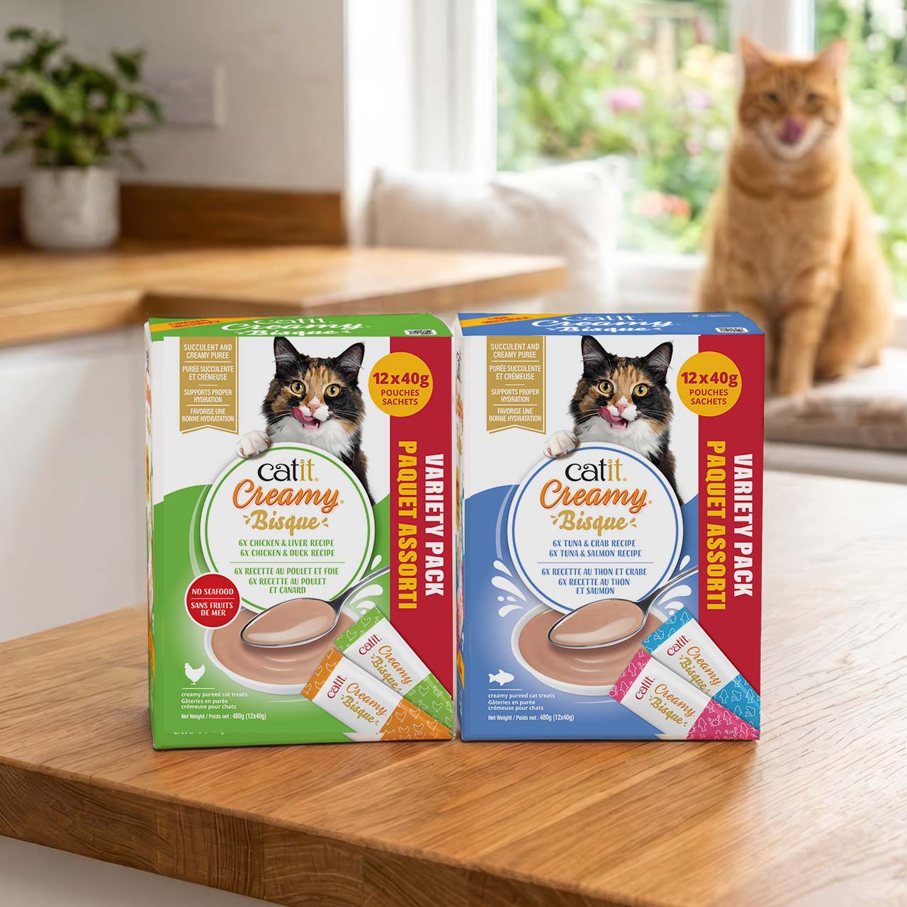 Catit Creamy Bisque Multipacks on a wooden kitchen counter with in the background a ginger cat licking it's face