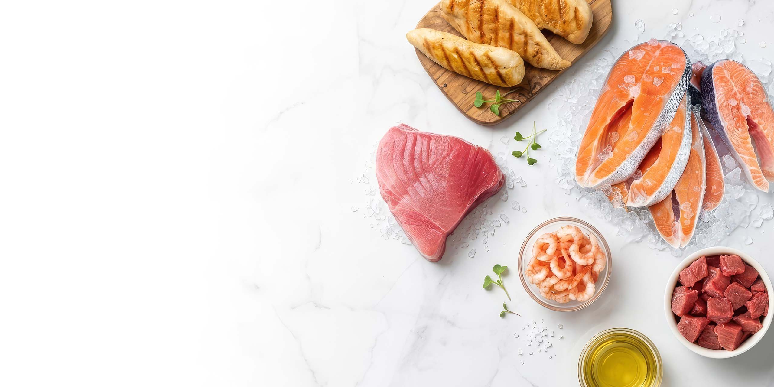 Raw salmon, tuna, shrimp, cubed beef, and grilled chicken on a marble surface